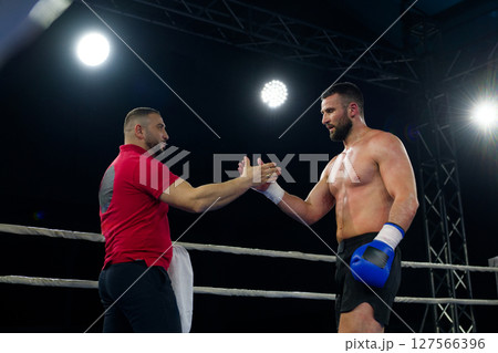 A boxer celebrates victory with his team in an emotional embrace after a grueling match. 127566396
