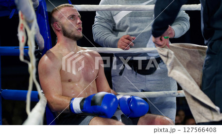 Cornered boxer receives strategic advice from trainer during intense bout. Cornered boxer receives strategic advice from trainer during intense bout. 127566408