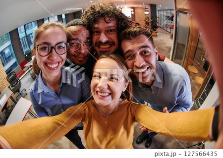 A diverse group of business professionals take a break from their tasks in a modern startup office to capture a creative selfie, showcasing teamwork and a vibrant workplace culture A diverse group of business professionals take a break from their tasks in a modern startup office to capture a creative selfie, showcasing teamwork and a vibrant workplace culture 127566435