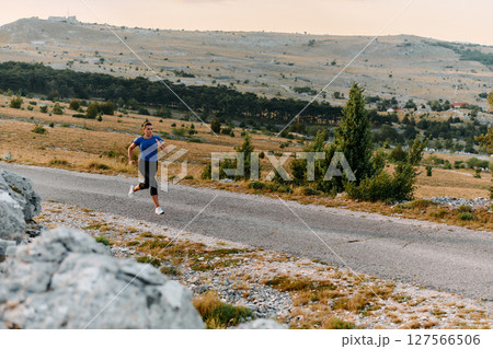 Empowered Runner Embracing Nature's Beauty on a Serene Morning Trail. 127566506