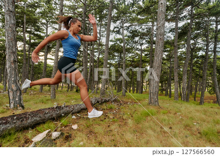 Fearless Woman Conquering Wooden Obstacles in the Dangerous Forest Terrain. 127566560