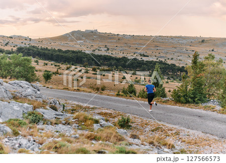 Empowered Runner Embracing Nature's Beauty on a Serene Morning Trail. 127566573