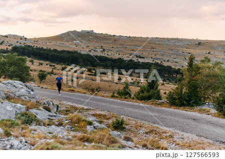 Empowered Runner Embracing Nature's Beauty on a Serene Morning Trail. 127566593