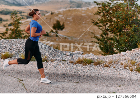 Empowered Runner Embracing Nature's Beauty on a Serene Morning Trail. 127566604