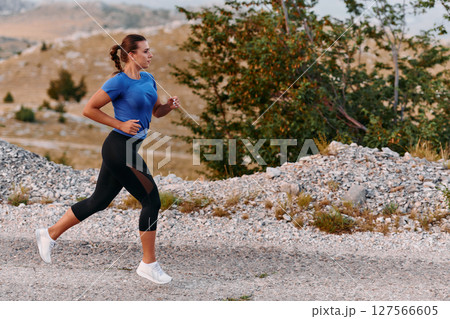 Empowered Runner Embracing Nature's Beauty on a Serene Morning Trail. 127566605