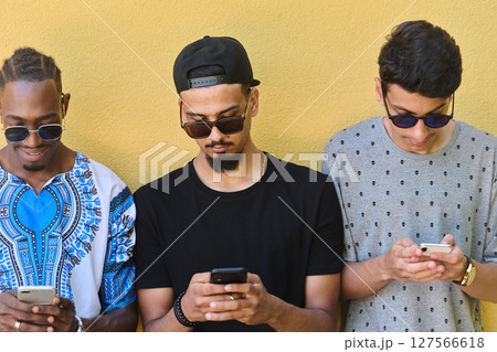 Diverse Teen Group Standing Together Against Wall Using Smartphones Diverse Teen Group Standing Together Against Wall Using Smartphones 127566618