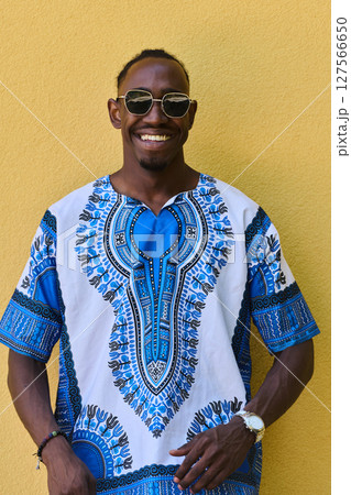 Sudanese Tradition Meets Modern Youth: African American Teen in Vibrant Traditional Attire Against a Yellow Backdrop Sudanese Tradition Meets Modern Youth: African American Teen in Vibrant Traditional Attire Against a Yellow Backdrop 127566650
