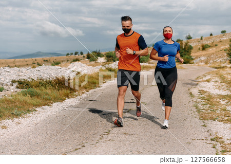 Couple running in nature at morning wearing protective face masks Couple running in nature at morning wearing protective face masks 127566658