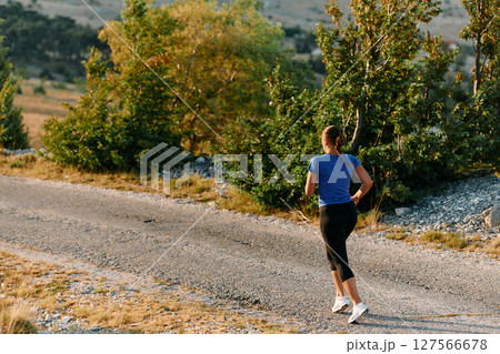 Empowered Runner Embracing Nature's Beauty on a Serene Morning Trail. 127566678
