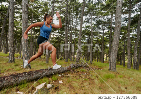 Fearless Woman Conquering Wooden Obstacles in the Dangerous Forest Terrain. Fearless Woman Conquering Wooden Obstacles in the Dangerous Forest Terrain. 127566689