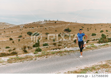 Determined Female Athlete Stretching After an Intense Run Through Rugged Mountain Terrain. Determined Female Athlete Stretching After an Intense Run Through Rugged Mountain Terrain. 127566690