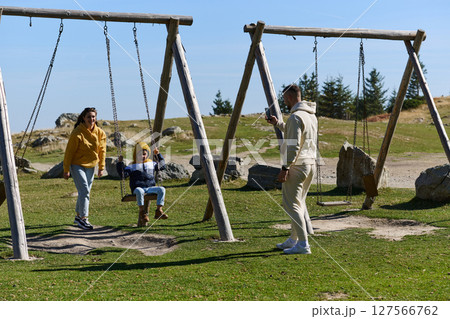 A modern family, along with their son, revels in the joy of a muddy day in nature, running and playing together, encapsulating the beauty of a healthy and active lifestyle 127566762