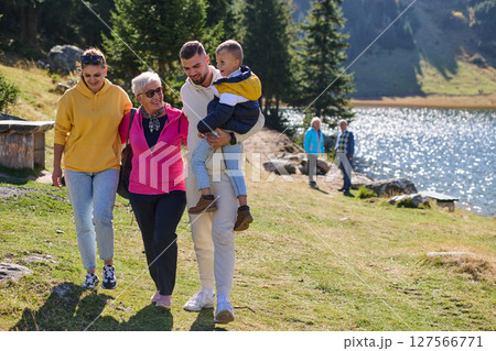 A family shares delightful moments with their friends amid the stunning landscapes of mountains, lakes, and winding paths, promoting a healthy lifestyle and the joy of familial bonds in the embrace of 127566771