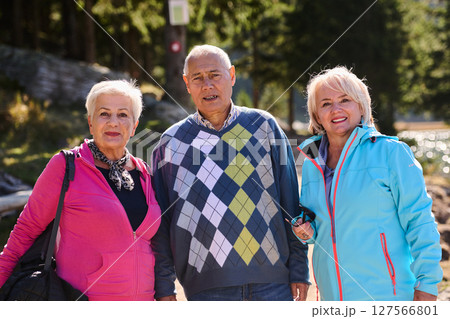 A family shares delightful moments with their friends amid the stunning landscapes of mountains, lakes, and winding paths, promoting a healthy lifestyle and the joy of familial bonds in the embrace of 127566801