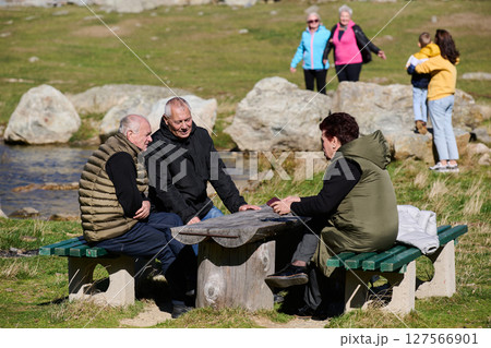 A family shares delightful moments with their friends amid the stunning landscapes of mountains, lakes, and winding paths, promoting a healthy lifestyle and the joy of familial bonds in the embrace of 127566901