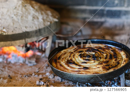 Capturing the essence of Bosnian culinary tradition, step-by-step preparation of a traditional Bosnian pie, showcasing the meticulous craftsmanship and authentic flavors involved in the culinary Capturing the essence of Bosnian culinary tradition, step-by-step preparation of a traditional Bosnian pie, showcasing the meticulous craftsmanship and authentic flavors involved in the culinary 127566905