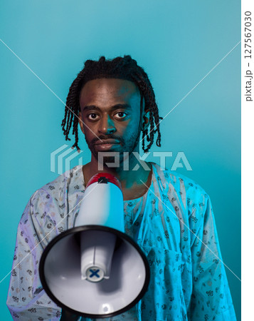 African American man dons traditional attire, passionately utilizing a megaphone against a striking blue background, symbolizing his vocal and cultural empowerment in the pursuit of social justice and African American man dons traditional attire, passionately utilizing a megaphone against a striking blue background, symbolizing his vocal and cultural empowerment in the pursuit of social justice and 127567030