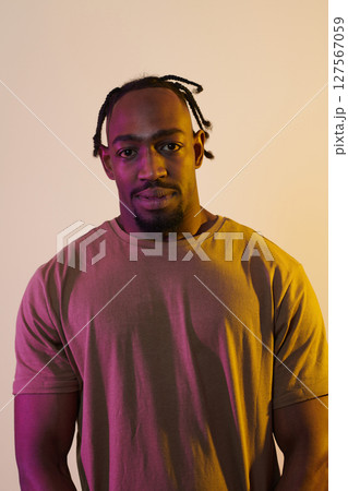 A charismatic and stylish African American man commands attention against a vibrant yellow gel background, showcasing his confident and contemporary fashion sense, radiating charm and sophistication 127567059