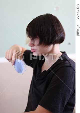 Young person brushing bowl cut hairstyle with lavender comb Young person brushing bowl cut hairstyle with lavender comb 127567185