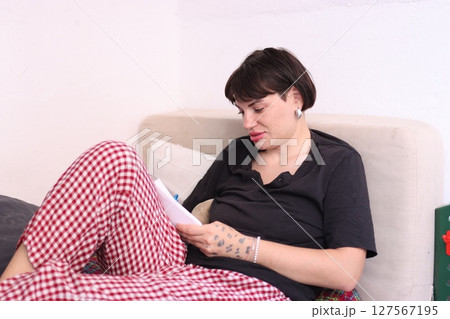Young woman writing on notepad while relaxing on bed 127567195