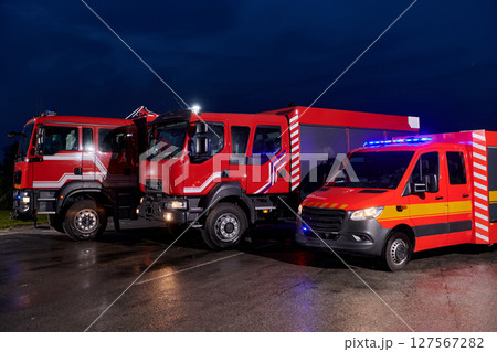A pair of highly modern and quality fire trucks illuminate the night with their rotating lights, symbolizing the cutting-edge technology and preparedness of the firefighting fleet, ready to respond to 127567282