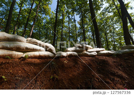 a military unit strategically employs sandbags as a defensive wall, creating a fortified barrier to enhance their safety and protection, showcasing the tactical use of simple yet effective measures a military unit strategically employs sandbags as a defensive wall, creating a fortified barrier to enhance their safety and protection, showcasing the tactical use of simple yet effective measures 127567336