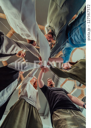 A group of young businessmen offer their hands together, symbolizing togetherness in the business world A group of young businessmen offer their hands together, symbolizing togetherness in the business world 127567572