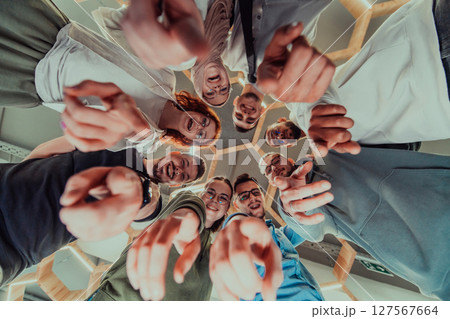 In a modern office, a group of young business professionals is captured in a warm and embracing hug, reflecting the spirit of unity, collaboration, and shared success in their dynamic workplace. 127567664