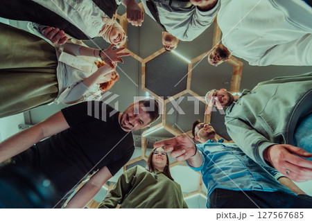 A group of young businessmen offer their hands together, symbolizing togetherness in the business world A group of young businessmen offer their hands together, symbolizing togetherness in the business world 127567685