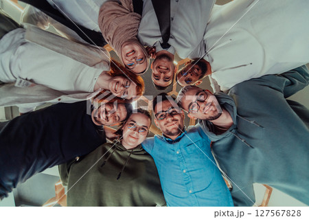 In a modern office, a group of young business professionals is captured in a warm and embracing hug, reflecting the spirit of unity, collaboration, and shared success in their dynamic workplace. In a modern office, a group of young business professionals is captured in a warm and embracing hug, reflecting the spirit of unity, collaboration, and shared success in their dynamic workplace. 127567828