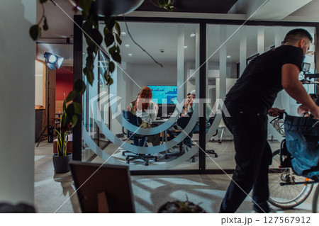 In a modern office, a professional team of videographers captures the essence of creativity and innovation as they film a group of young entrepreneurs, symbolizing collaboration and ambition in the 127567912