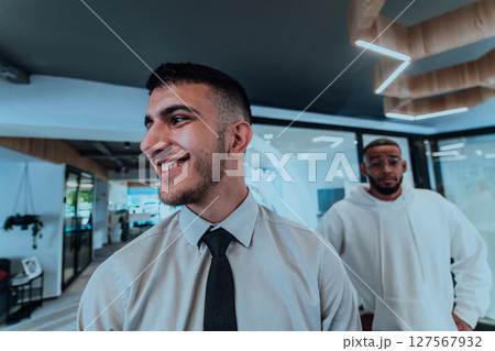 A group of young business professionals stands together, taking a well-deserved break from their busy workday, showcasing camaraderie, teamwork, and a moment of relaxation in their dynamic workplace 127567932