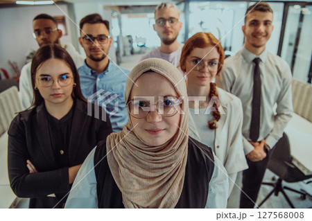 A group of young business professionals stands together, taking a well-deserved break from their busy workday, showcasing camaraderie, teamwork, and a moment of relaxation in their dynamic workplace 127568008