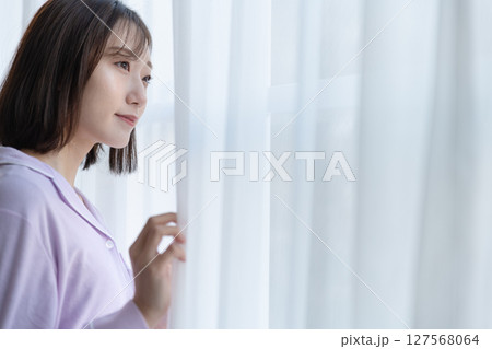 レースのカーテンの隙間からで外を見ている若い女性 レースのカーテンの隙間からで外を見ている若い女性 127568064
