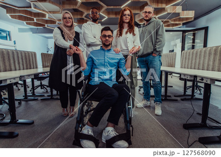 Young businessmen in a modern office extend a handshake to their business colleague in a wheelchair, showcasing inclusivity, support, and unity in the corporate environment. 127568090