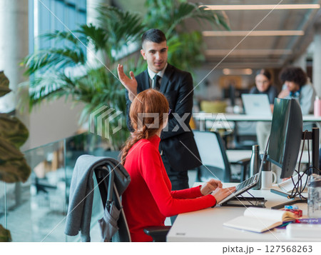 In a modern startup office, a diverse group of young professionals collaboratively tackles various business problems and challenges, surrounded by their engaged colleagues, fostering innovation and 127568263
