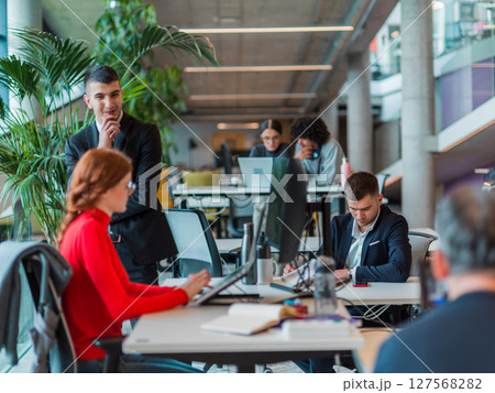 In a modern startup office, a diverse group of young professionals collaboratively tackles various business problems and challenges, surrounded by their engaged colleagues, fostering innovation and 127568282