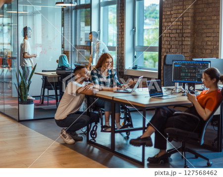 A diverse group of young business individuals congregates in a modern startup coworking center, embodying collaborative innovation and a dynamic atmosphere 127568462