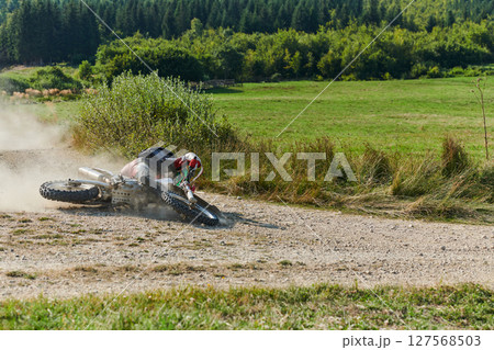 A professional motocross rider experiences an unfortunate fall from their motorcycle on a forest trail, highlighting the dangers of off-road racing. A professional motocross rider experiences an unfortunate fall from their motorcycle on a forest trail, highlighting the dangers of off-road racing. 127568503