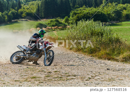 A professional motocross rider exhilaratingly riding a treacherous off-road forest trail on their motorcycle. A professional motocross rider exhilaratingly riding a treacherous off-road forest trail on their motorcycle. 127568516