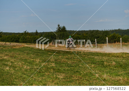 A professional motocross rider exhilaratingly riding a treacherous off-road forest trail on their motorcycle. A professional motocross rider exhilaratingly riding a treacherous off-road forest trail on their motorcycle. 127568522