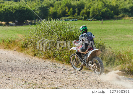 A professional motocross rider exhilaratingly riding a treacherous off-road forest trail on their motorcycle. 127568591