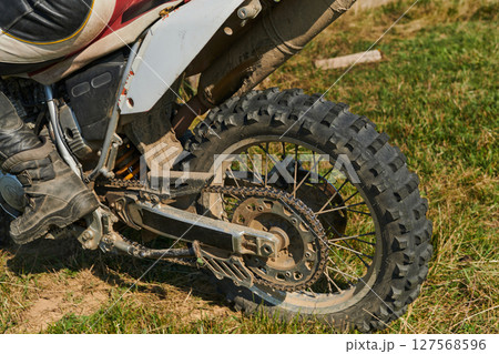 Close up photo of a professional motocross rider in action, showcasing the tire and various components of the motorcycle as they navigate the challenging off-road terrain with speed and precision. 127568596