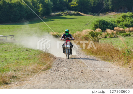 A professional motocross rider exhilaratingly riding a treacherous off-road forest trail on their motorcycle. 127568600