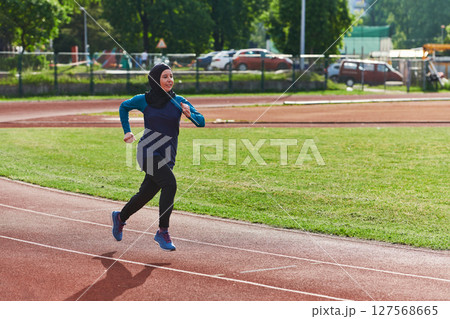 A muslim woman in a burqa sports muslim clothes running on a marathon course and preparing for upcoming competitions 127568665