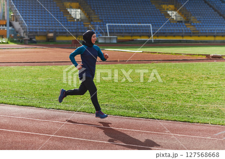 A muslim woman in a burqa sports muslim clothes running on a marathon course and preparing for upcoming competitions 127568668