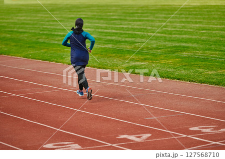 A muslim woman in a burqa sports muslim clothes running on a marathon course and preparing for upcoming competitions 127568710