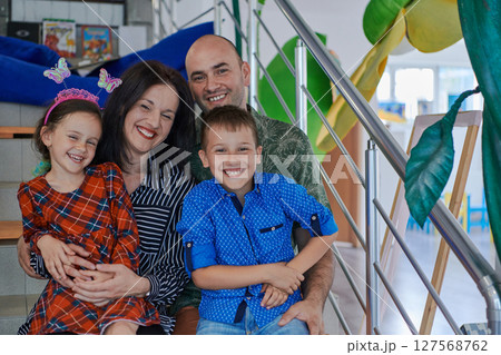 Portrait of a happy family. Photo of parents with children in a modern preschool classroom. Selective focus Portrait of a happy family. Photo of parents with children in a modern preschool classroom. Selective focus 127568762