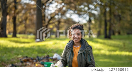 Smiling Young Volunteer Cleaning Up Trash in a Park.Generated image 127568953