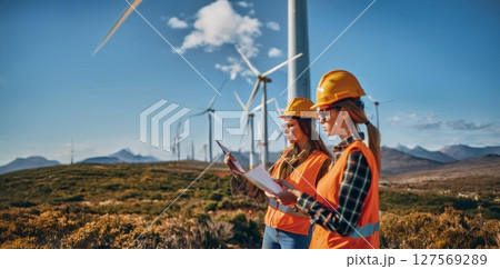 Female engineers using tablets to monitor and manage wind turbine operations on site.Generated image 127569289